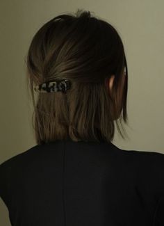 the back of a woman's head wearing a black shirt and a hair clip