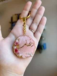 a hand holding a keychain with an arabic writing on it