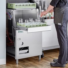 a man standing in front of a machine filled with glasses and bottles on it's side