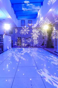 an indoor dance floor with snowflakes on it and lights shining down the center