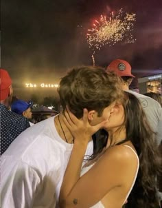 a man and woman kissing with fireworks in the sky behind them at a sporting event