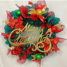 a christmas wreath with the words merry christmas written in gold and green letters on it