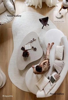 a woman laying on top of a white couch in a living room