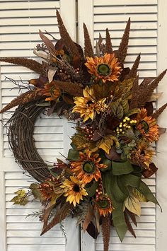 a wreath with sunflowers and leaves hanging on a door