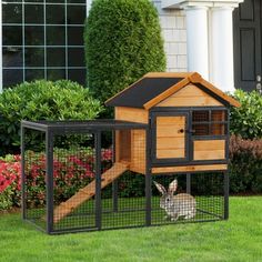 a small wooden house with a rabbit in it's cage next to some bushes