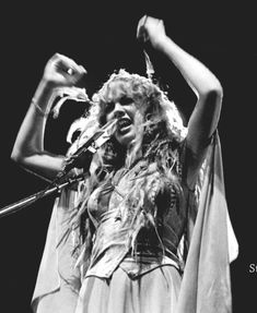 a black and white photo of a woman holding a microphone in her right hand while singing