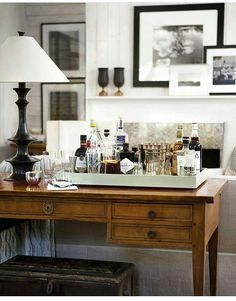 a wooden table topped with lots of bottles and glasses next to a white couch in a living room