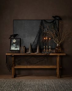 a wooden table topped with candles next to a painting and pictures on top of it