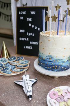 a birthday cake with stars on top and a rocket ship decoration next to it,