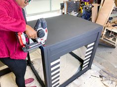 a woman sanding up a table with a power tool