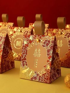 four small bags with gold foil designs on them and some candy in front of them