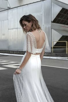 a woman in a white dress is walking down the street with her back to the camera