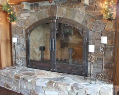 a stone fireplace with two candles on each side and a mirror over the fire place