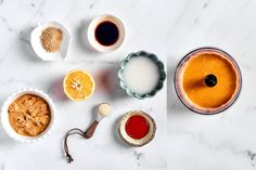 an assortment of food items on a white counter top, including oranges and other condiments