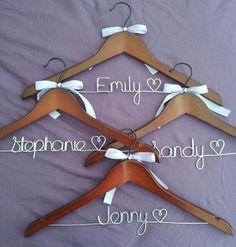 three wooden clothes hangers with names and hearts attached to them on a purple sheet