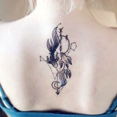 the back of a woman's neck with a tattoo design on her left shoulder