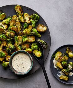 a black plate topped with brussel sprouts next to a bowl of dipping sauce