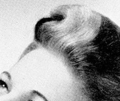 a black and white photo of a woman's face with her hair in a bun