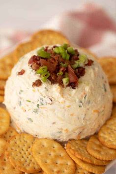 a cheese ball with bacon and green onions on top is surrounded by cracker chips