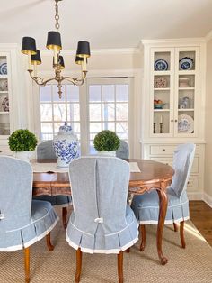 a dining room table with blue chairs and china cabinet in the backround area