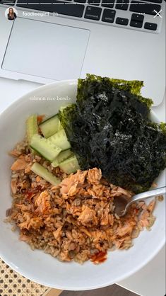 a white plate topped with rice and veggies next to a lap top computer