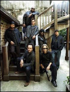 a group of men standing on top of stairs next to each other in front of a brick building