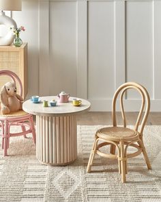 two children's chairs and a table in a room with white paneled walls