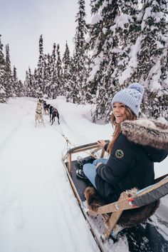 a woman riding on the back of a sled down a snow covered slope