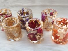 several different colored glass vases sitting next to each other on a white tablecloth