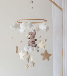 a teddy bear sitting on top of a cloud mobile in the shape of a star