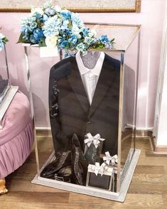 a mannequin dressed in a tuxedo and shoes is displayed on a table