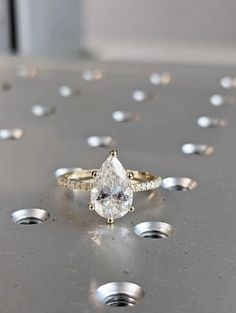 a diamond ring sitting on top of a metal table with lots of diamonds around it