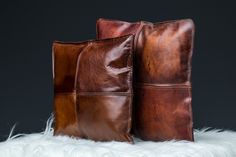 two brown leather pillows sitting on top of white fur