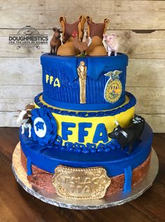 a three tiered cake with animals and letters on the top, in front of a wooden wall