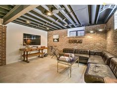 a living room filled with lots of furniture and exposed ceiling beams in an industrial style home