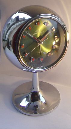 a chrome clock sitting on top of a metal stand