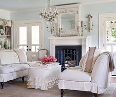 a living room filled with furniture and a fire place under a chandelier in front of a fireplace