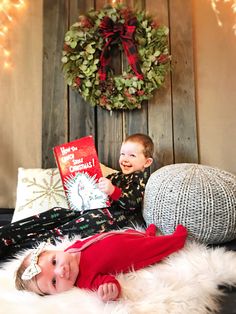 a little boy laying on top of a bed next to a christmas wreath and a book