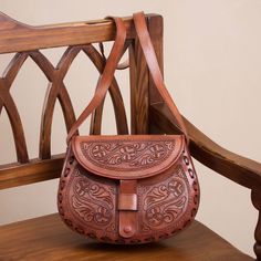 a brown leather purse sitting on top of a wooden chair