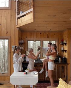 three women standing around in a room with wooden walls