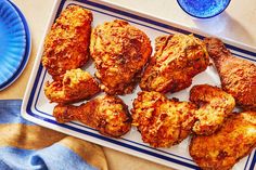 chicken wings on a plate next to a glass of water and a blue dish towel