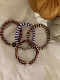 three bracelets on a bed next to a teddy bear