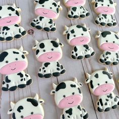 decorated cookies with black and white cows are on a wooden table next to each other