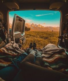 a person laying in the back of a truck with their feet up on a blanket