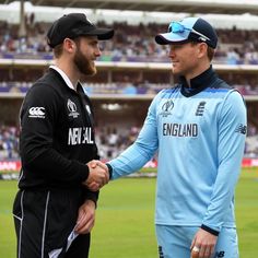 two men shaking hands in front of a crowd at a cricket match on a grass field