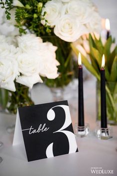 a table with candles and flowers in vases on it, next to a card that says table 2