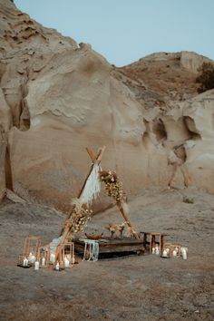 a teepee is set up in the desert for an outdoor ceremony with candles and flowers