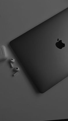 an apple laptop computer sitting on top of a table next to ear buds and headphones