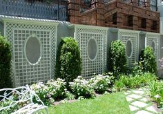 a white bench sitting on top of a lush green field next to a fence covered in flowers