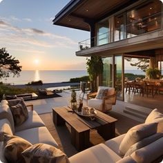 an outdoor living room with couches and tables overlooking the ocean at sunset or sunrise